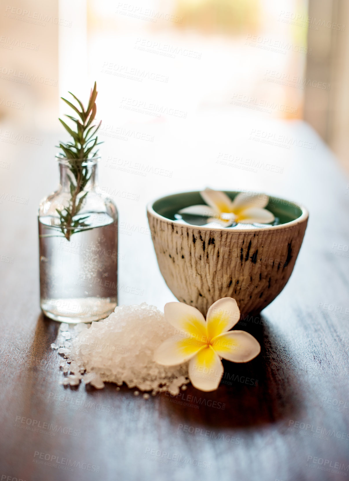 Buy stock photo Wellness, spa salt and essential oil with flowers on table for aromatherapy treatment, relax or swedish massage. Interior decoration, luxury space and empty room with organic products for hospitality