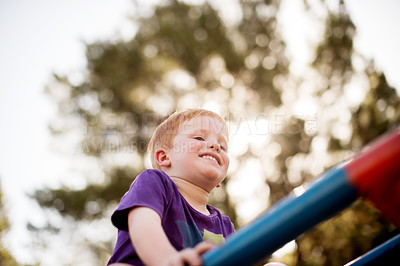Buy stock photo Merry go round, play and smile of boy outdoor in nature for child development, growth or having fun. Balance, happy and youth with excited kid on carousel from below for playground adventure