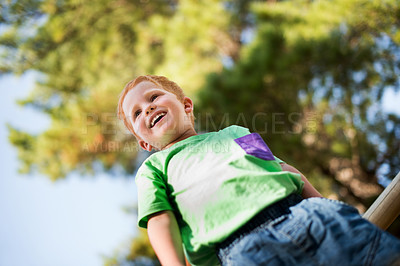 Buy stock photo Outdoor, happy and child in park playing for activity, learning and fun in nature for holiday. Excited, low angle and boy kid on playground equipment for development, growth or adventure in field.