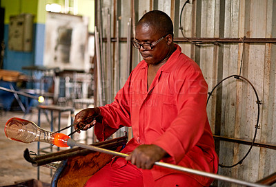 Buy stock photo Glass, blowing and black man in craft workshop for small business with heat, tools and technique. Creative, handmade product and glassblower in factory for sustainable art, design or bottle sculpture