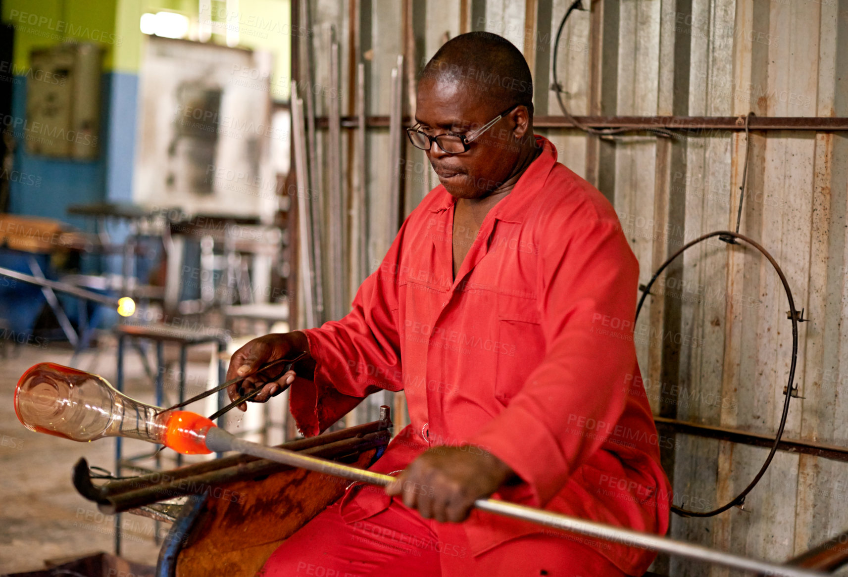 Buy stock photo Glass, blowing and black man in craft workshop for small business with heat, tools and technique. Creative, handmade product and glassblower in factory for sustainable art, design or bottle sculpture
