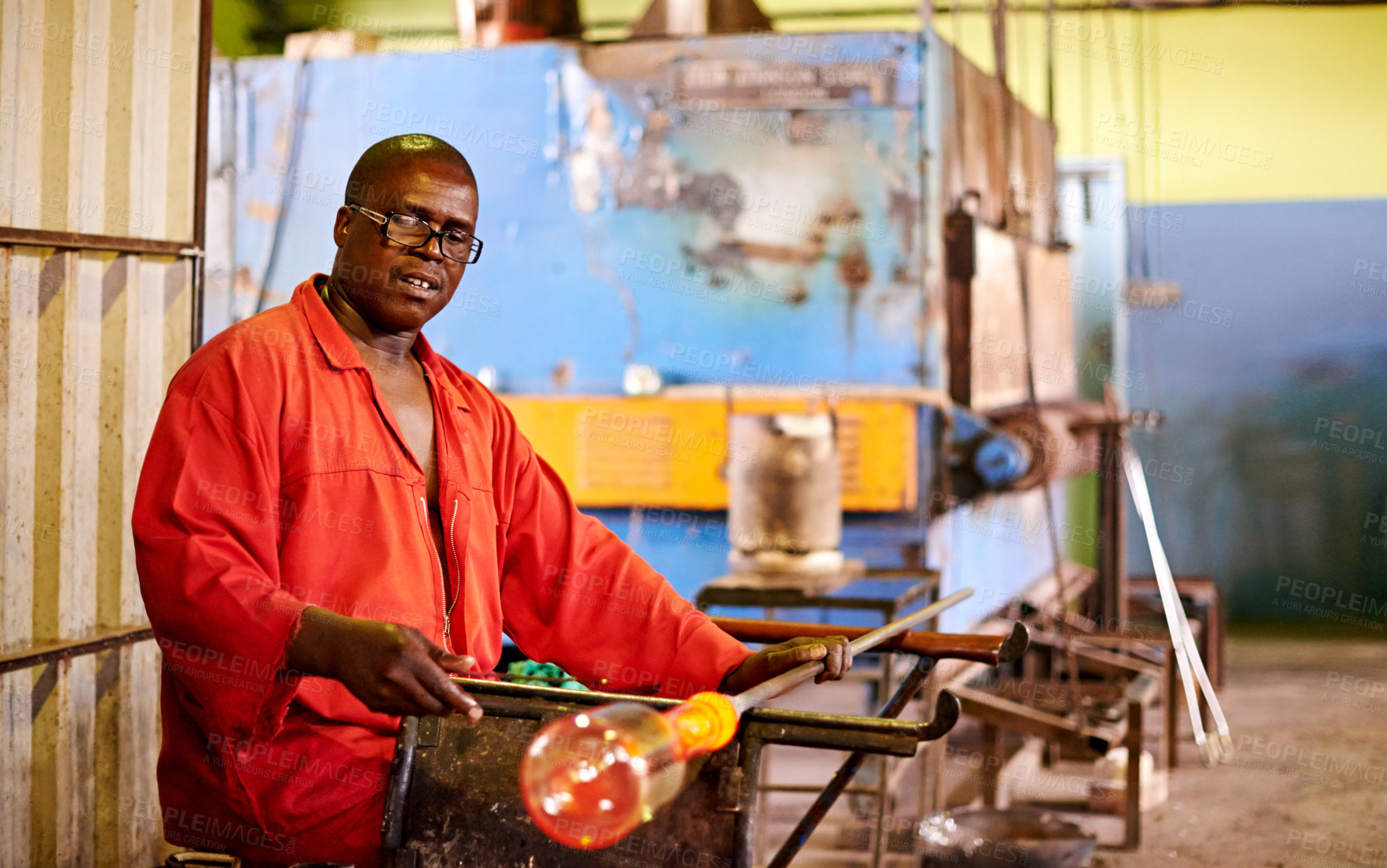 Buy stock photo Glassblowing, man and shaping of glass, factory and creative for manufacturing of product and industry. Production, busy and black person in uniform for craft, glassmaker or art for design with tools