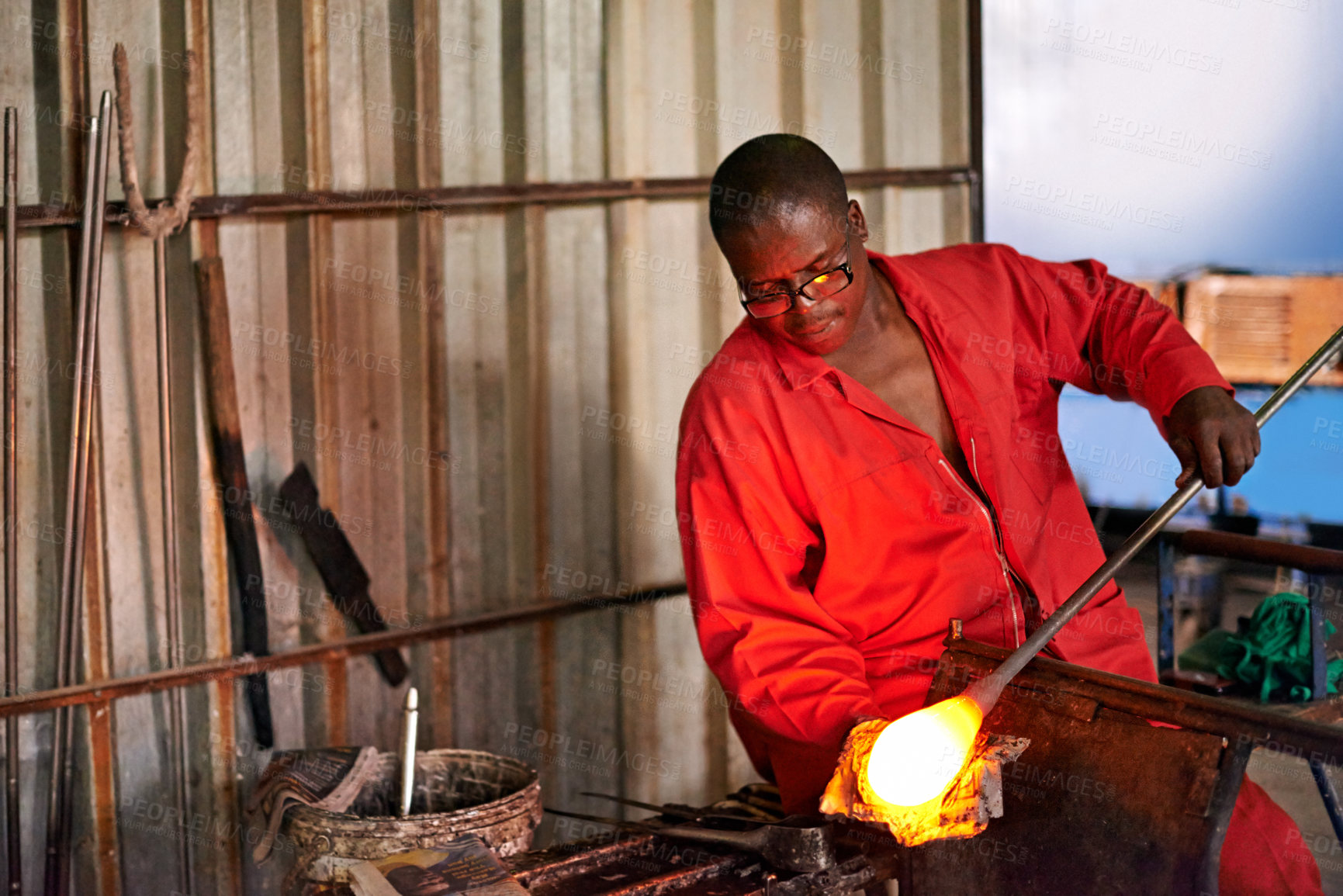 Buy stock photo Glass, blowing and black man in workshop with glow for small business, craft or handmade technique. Creative, product shape or glassblower in factory for sustainable process, design or sculpture art