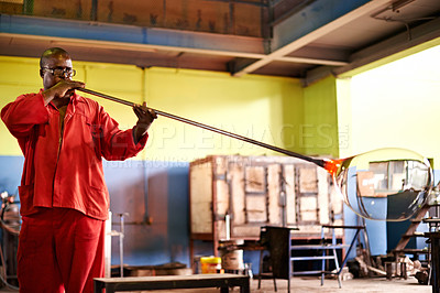Buy stock photo Glassblowing, glass and man with blowpipe, craft and serious for manufacturing, factory or industry. Production, shaping and black person in uniform for art, glassmaker or tools for design of product