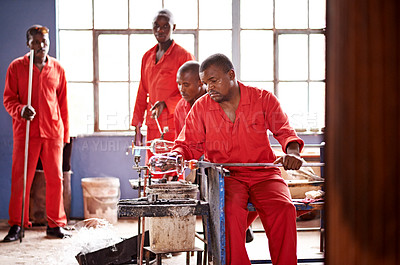 Buy stock photo Glassblower, craft and people in workshop for heating production or equipment for professional skills. Labor, factory or men molding object shape with tools for metalwork, manufacturing or teamwork