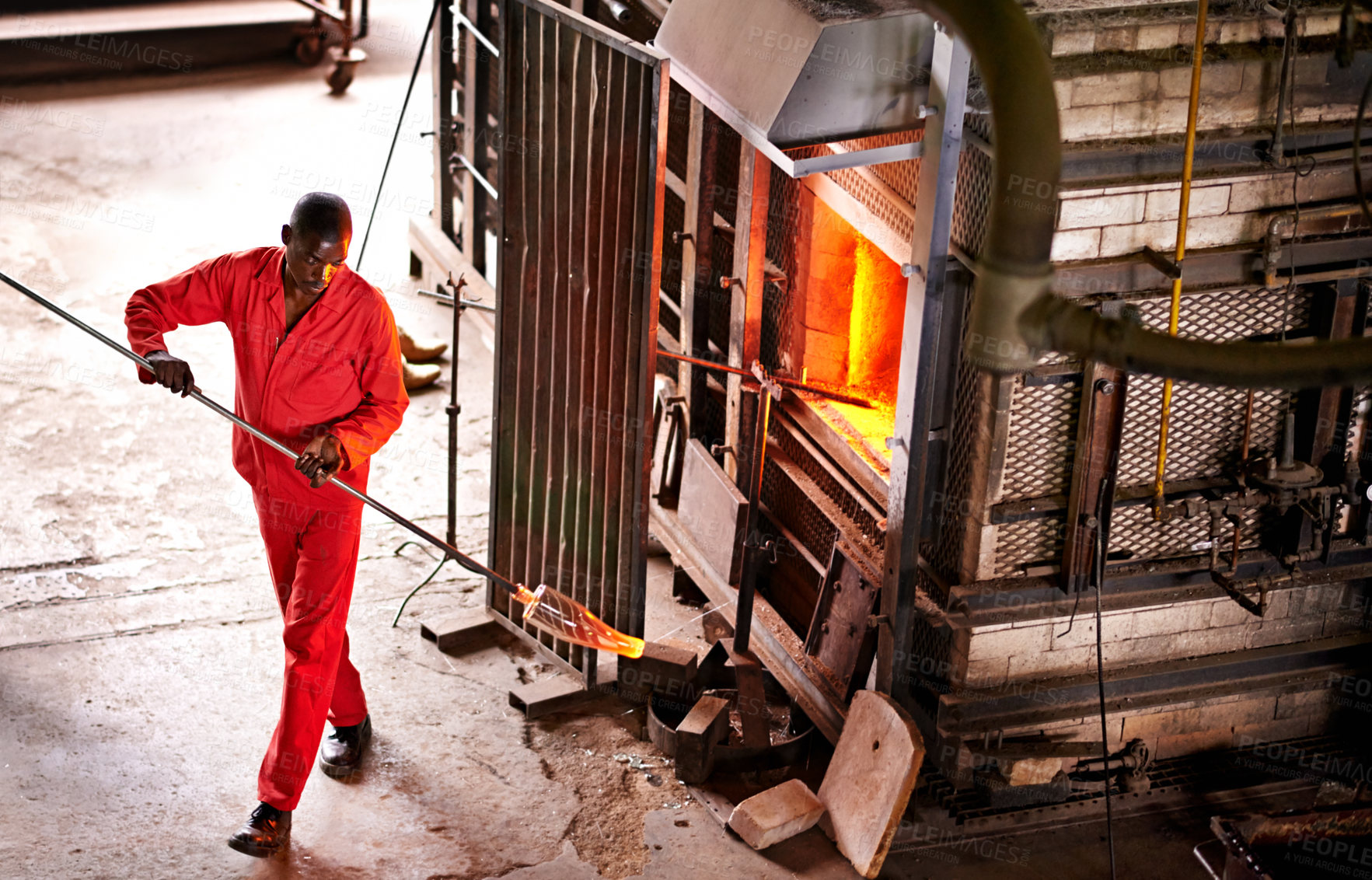 Buy stock photo Above, glassblower and black man in factory, furnace and equipment with tools, heat and industry. African person, technique and employee with material, skills and artistry with manufacturing and iron