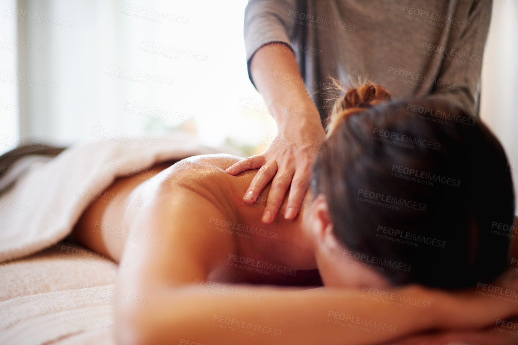 Buy stock photo Woman, relax and masseuse with massage at spa for beauty, physical therapy or body treatment at resort. Female person, lying and relaxation on bed at luxury salon for shoulder rub or stress relief