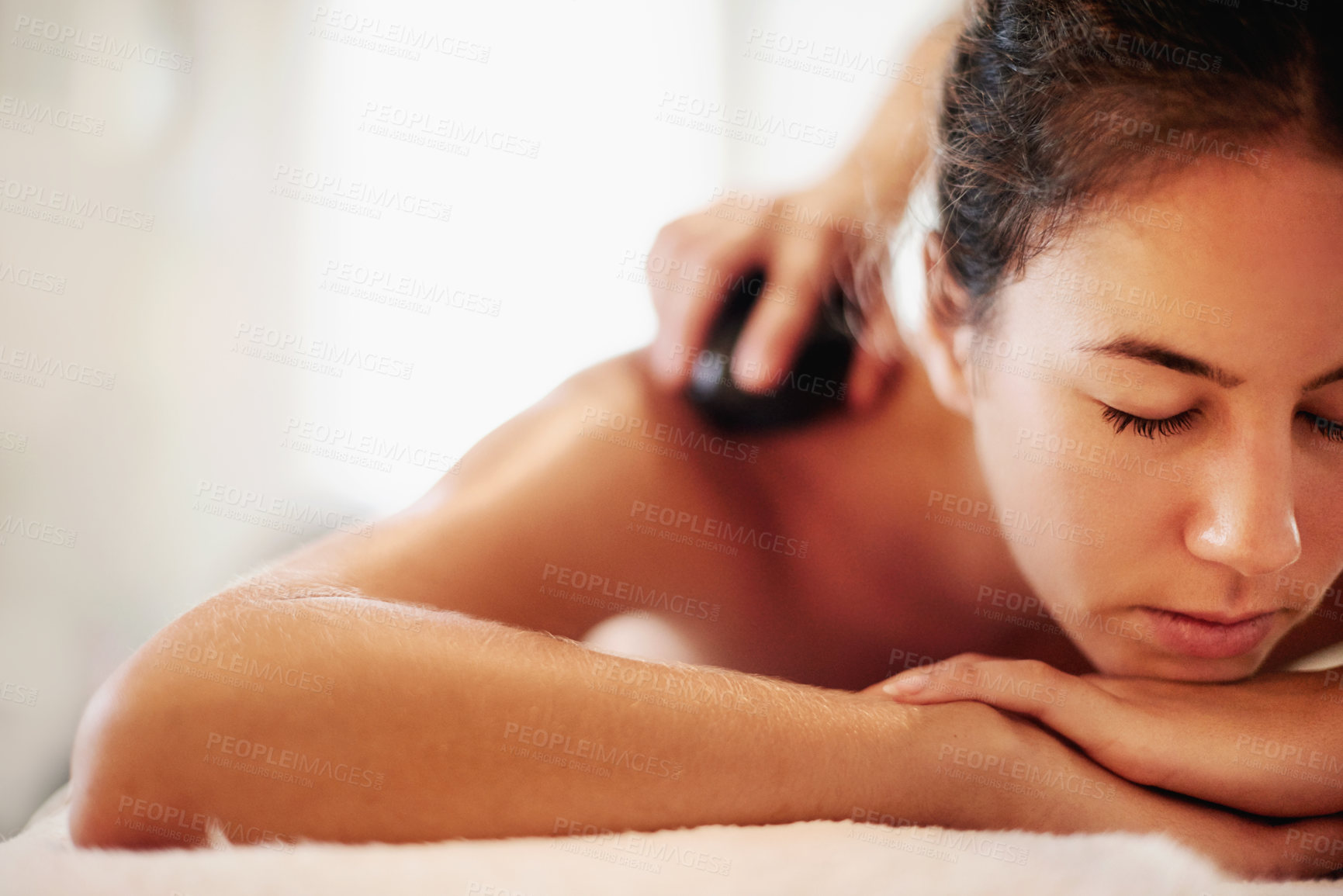 Buy stock photo Woman, spa and hot stone massage for back, muscle recovery and stress relief on holiday at resort. Person, masseuse and service with rock for circulation, relax and healing tissue at luxury lodge