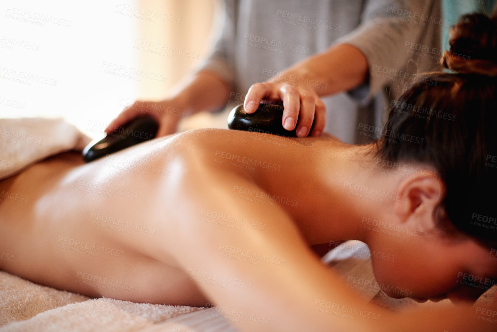 Buy stock photo Hands, spa and woman with hot stone for back, muscle recovery and rehabilitation on vacation at resort. Person, massage and lava rocks for circulation, relax and physical therapy at luxury lodge