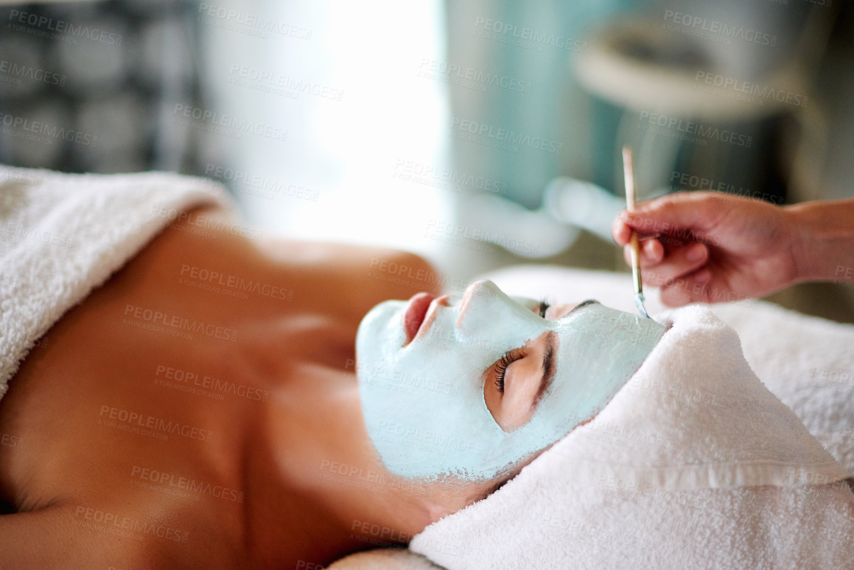 Buy stock photo Hands, mask and woman on spa bed with brush, treatment or exfoliate on holiday at luxury resort. Person, cosmetics and eyes closed for facial, cream or process for skincare, glow or benefits at lodge