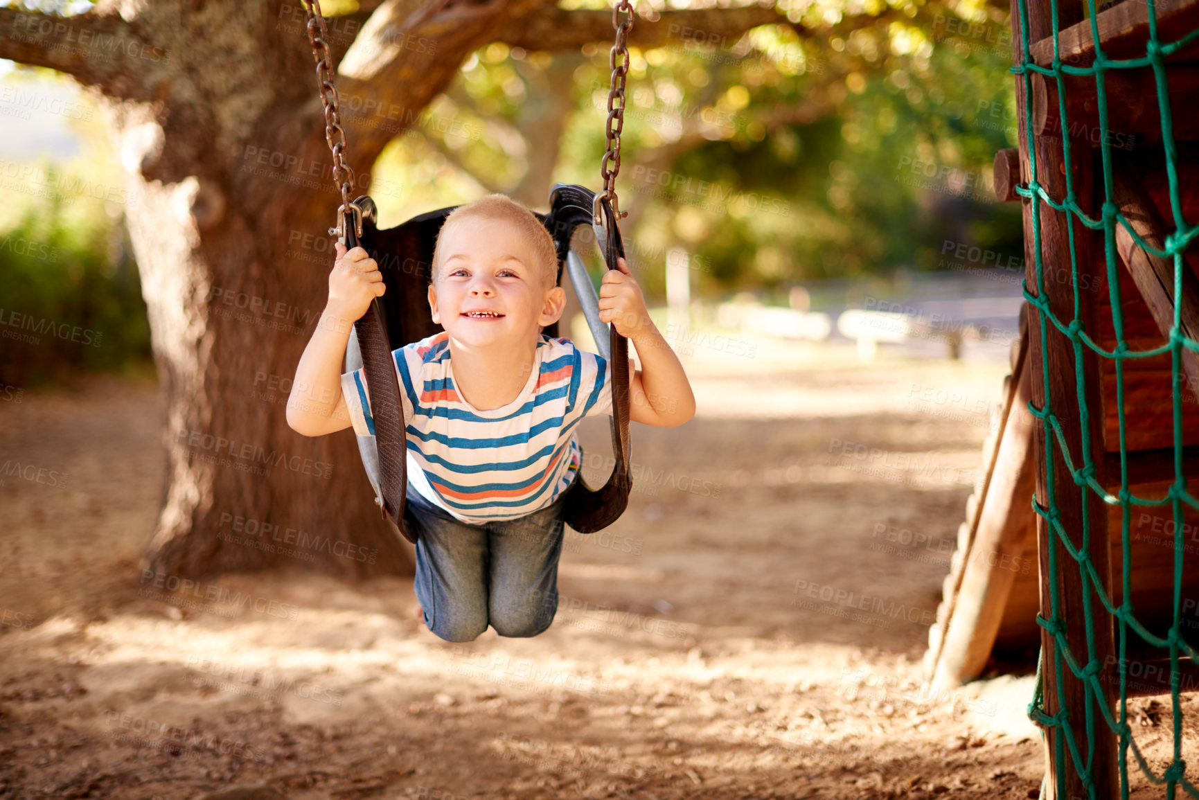 Buy stock photo Happy, swing and portrait of kid in park with play, outdoor adventure and fun child development in nature. Relax, wellness and boy in playground for growth, morning games or playful childhood weekend