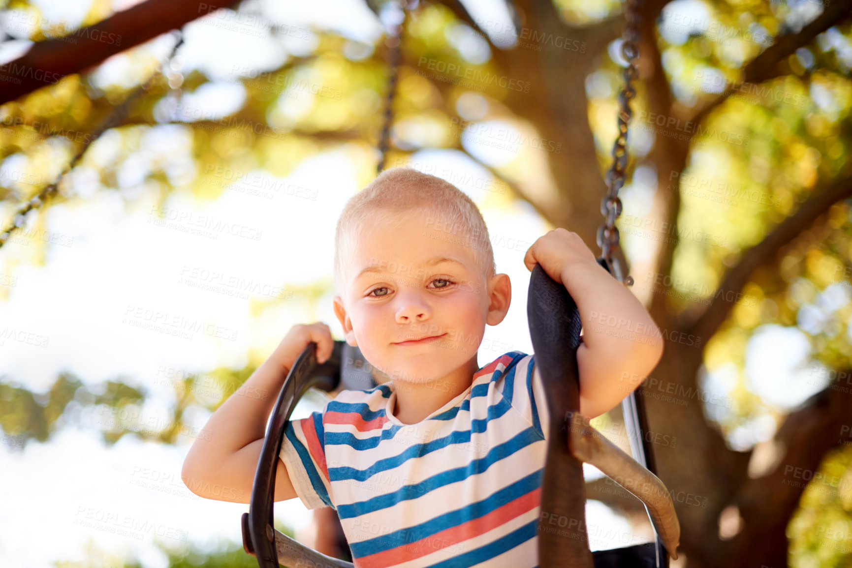 Buy stock photo Fun, swing and portrait of boy in park with trees, outdoor adventure and child development in nature. Play, smile and kid in playground for growth, games or summer childhood on weekend from below