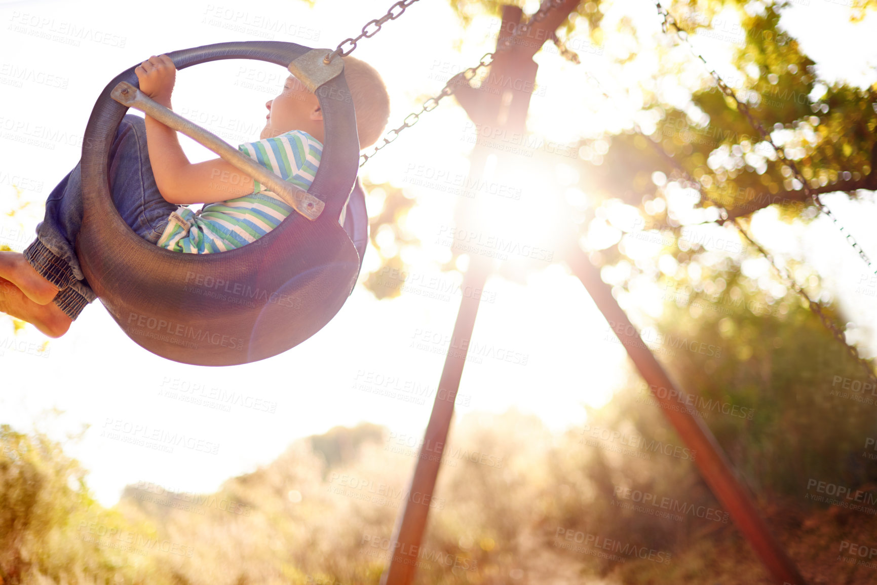 Buy stock photo Tree, swing and child in park with outdoor adventure, play and development for kids in nature. Sunshine, happy and boy in playground for growth, fun games or summer childhood on weekend from below