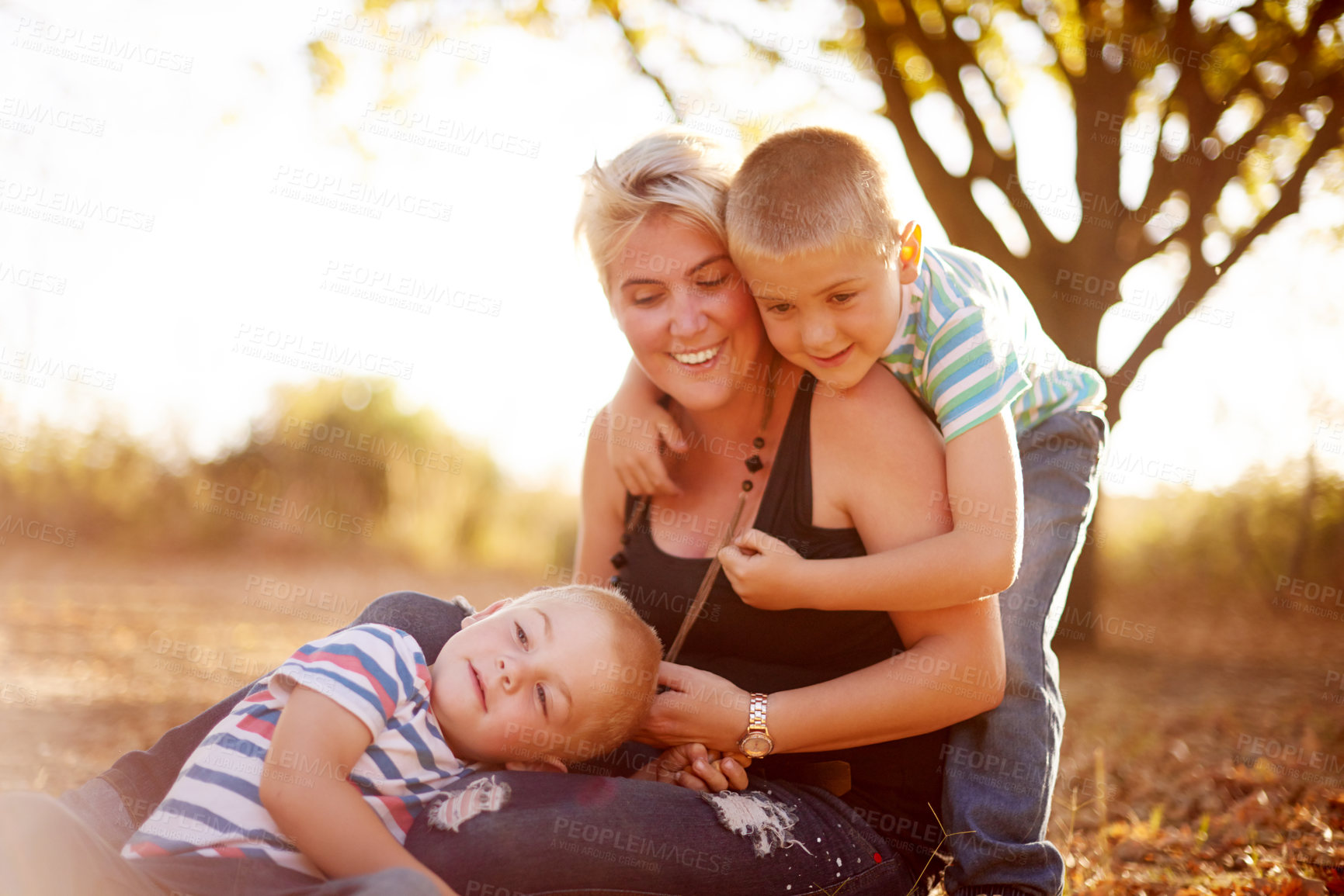 Buy stock photo Children, mother and hug on grass with love, support or relax at sunset on summer vacation. Happy woman, kids or playful in nature for family holiday, bonding or relationship development for wellness