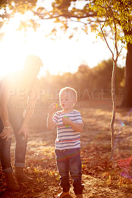 Buy stock photo Happy, blowing bubbles and child in park with mom for fun, childhood and bonding together outdoors. Family, sunlight and boy with soap, toys and activity for playing, adventure or game in nature