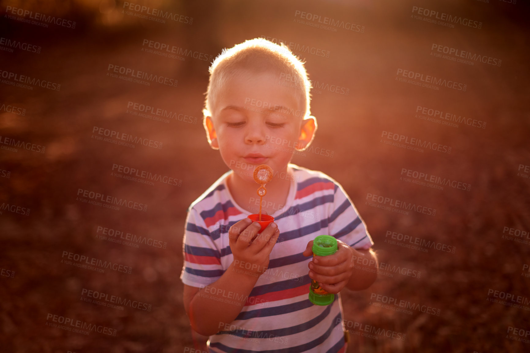Buy stock photo Boy, child and blowing bubbles at sunset, nature and outdoor at park with game, memory and playful in summer. Kid, toys and happy with soap, liquid and foam with development on adventure in Australia