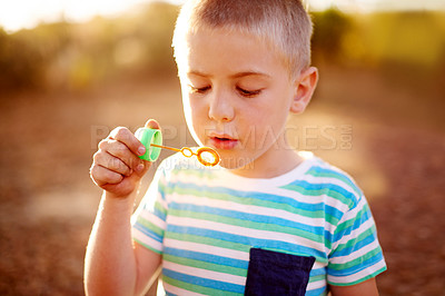 Buy stock photo Boy, kid and park for blowing bubbles at sunset, outdoor and games with memory in autumn. Child, toys and playful on adventure with soap, liquid and foam in sunshine for development in New Zealand
