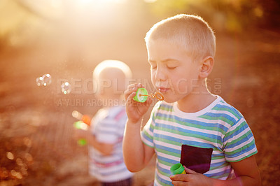 Buy stock photo Sunlight, blowing bubbles and children in nature for fun, childhood and bonding together outdoors. Family, summer and young brothers with soap, toys or activity for playing, adventure or game in park