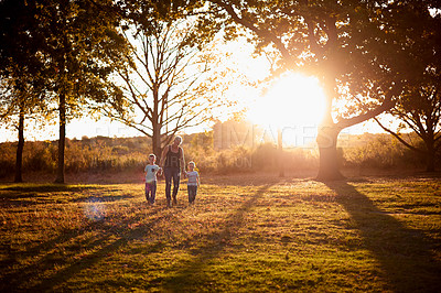 Buy stock photo Family, mother or holding hands with children in nature for bonding holiday or sunset at outdoor park. Mom, kids or siblings on grass field with sunlight or trees for playful adventure in countryside