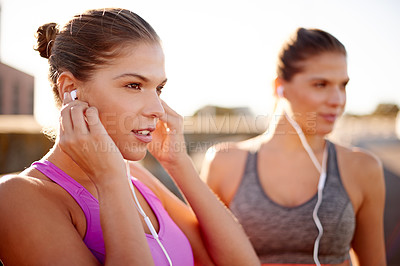 Buy stock photo Women, fitness and together with earphones in street for music, training and sisters in summer. People, runner and twins with streaming, subscription and happy for workout on urban bridge in Spain