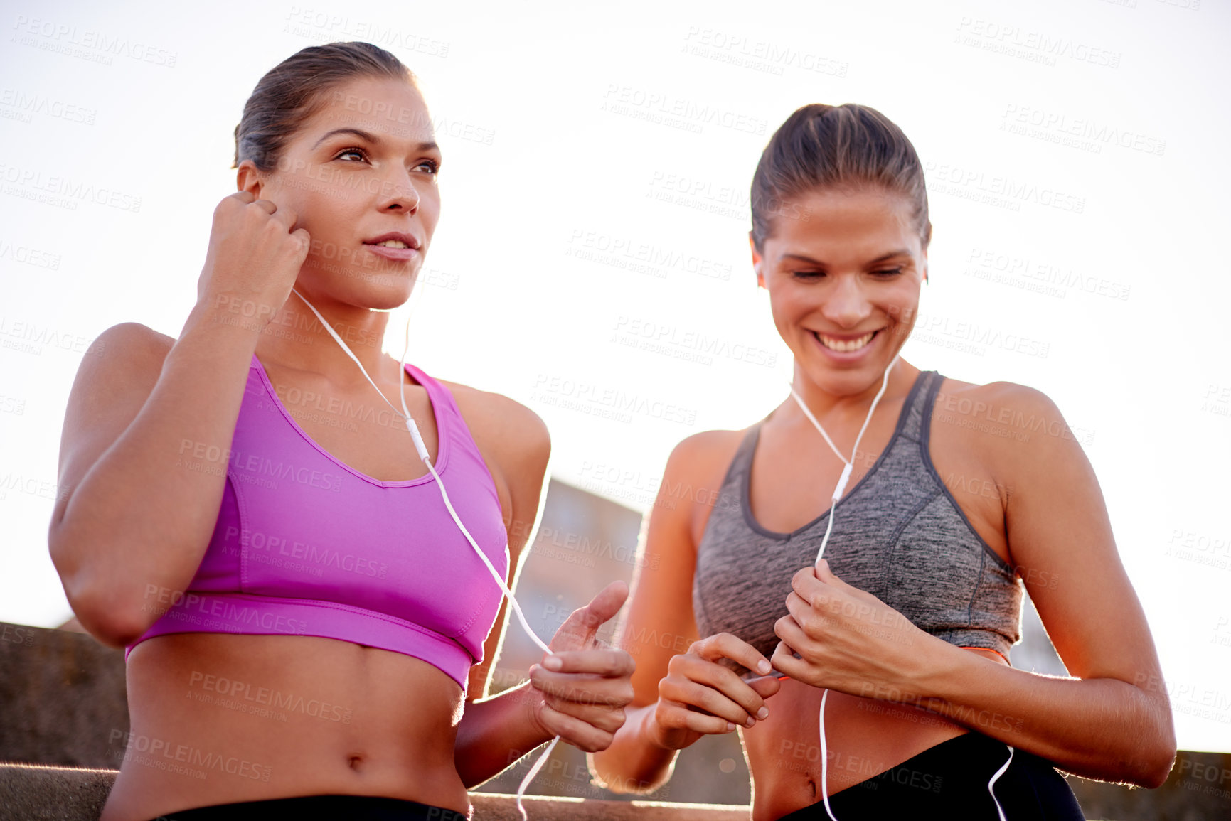 Buy stock photo City, women and smile with earphones for fitness, workout playlist and listening to audio outdoor. Happy people, sisters and break for training with music, wellness or podcast for exercise motivation