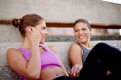 Buy stock photo Fitness, women and break with music outdoor for cardio challenge, listening to sound track and recovery. Twin teamwork, happy and relax on bridge with earphones for workout audio and training support