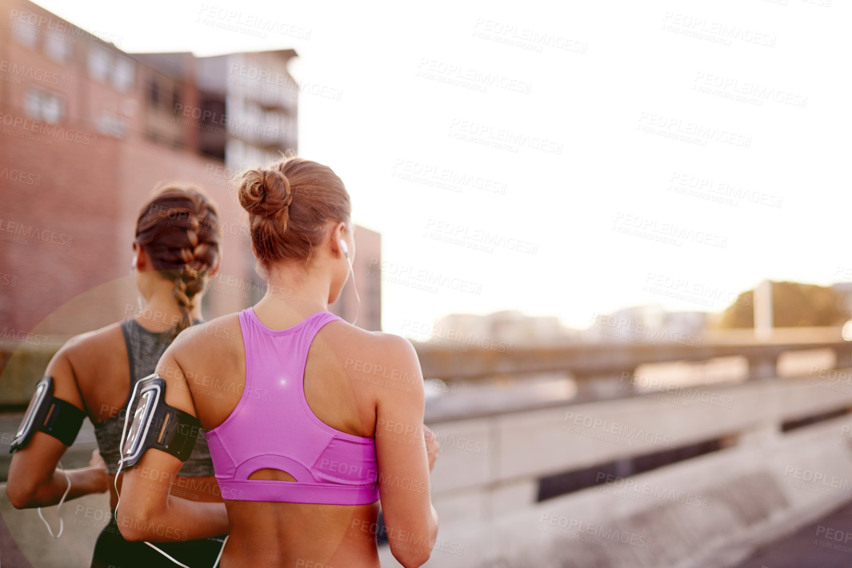 Buy stock photo Earphones, fitness and back of sisters in city for running with marathon training with music. Health, sports and women twins with audio tech for cardio workout or exercise on bridge in town together.