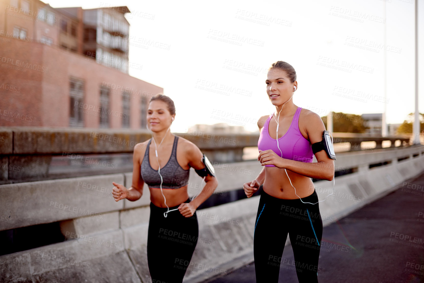 Buy stock photo Women, fitness and outdoor for running in town, streaming music and team support with exercise. Urban city, workout together and podcast for cardio sports, marathon training and earphones for audio