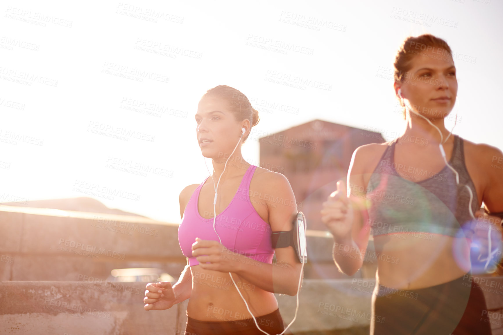 Buy stock photo Earphones, running and phone with women in city for health podcast, workout and exercise tracking. Runner, wellness and music with people training for sports athlete, twin sister or marathon