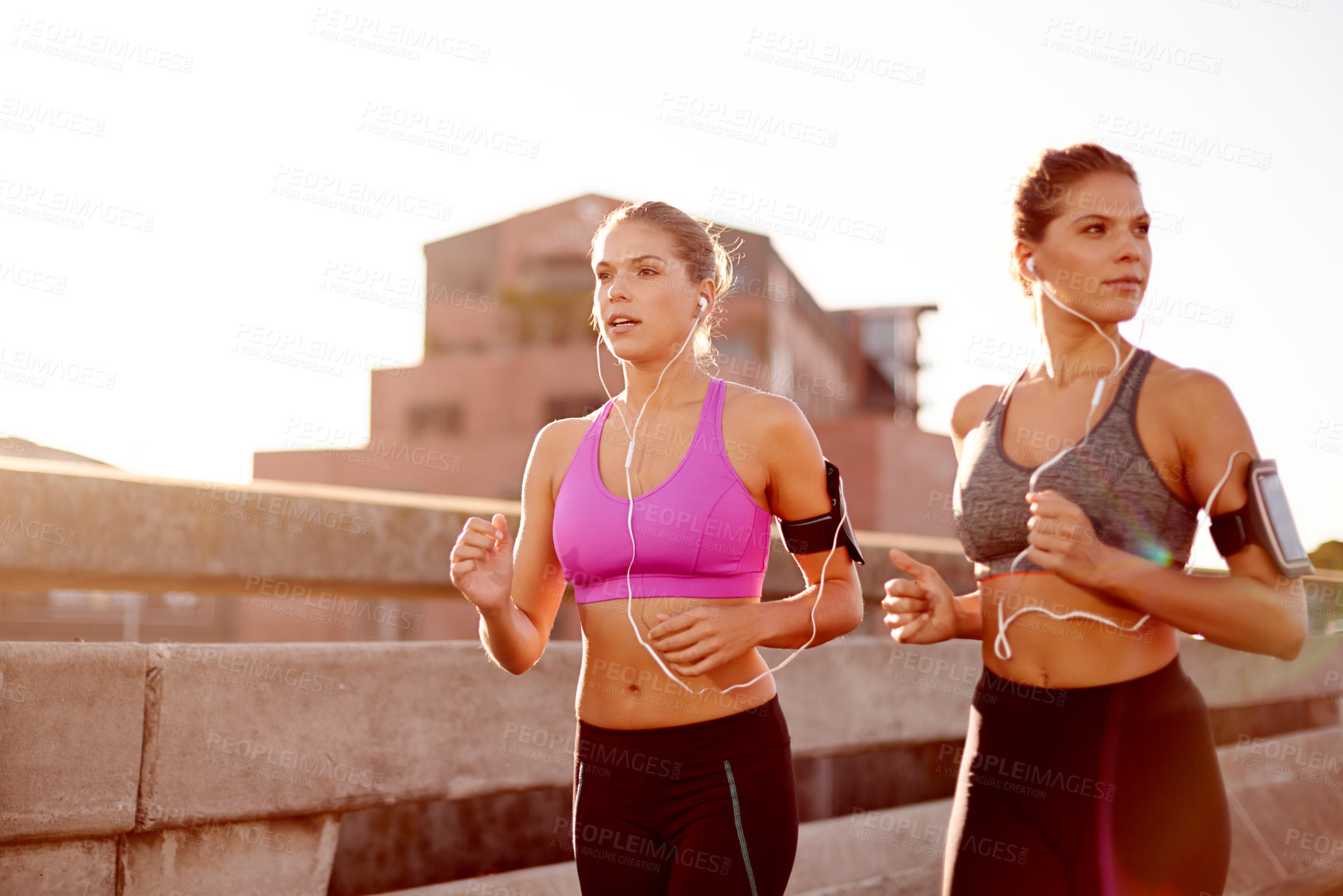 Buy stock photo Women, fitness and outdoor for cardio in city, streaming music and support with exercise. Urban town, workout together and twins for running practice, marathon training and earphones for podcast