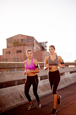 Buy stock photo Women, running and together on bridge with earphones, training and prepare for marathon in city. People, twins and sisters with exercise, streaming and cardio workout with mockup space in New Zealand