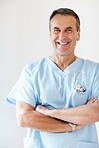 Confident medical doctor with hands folded against white