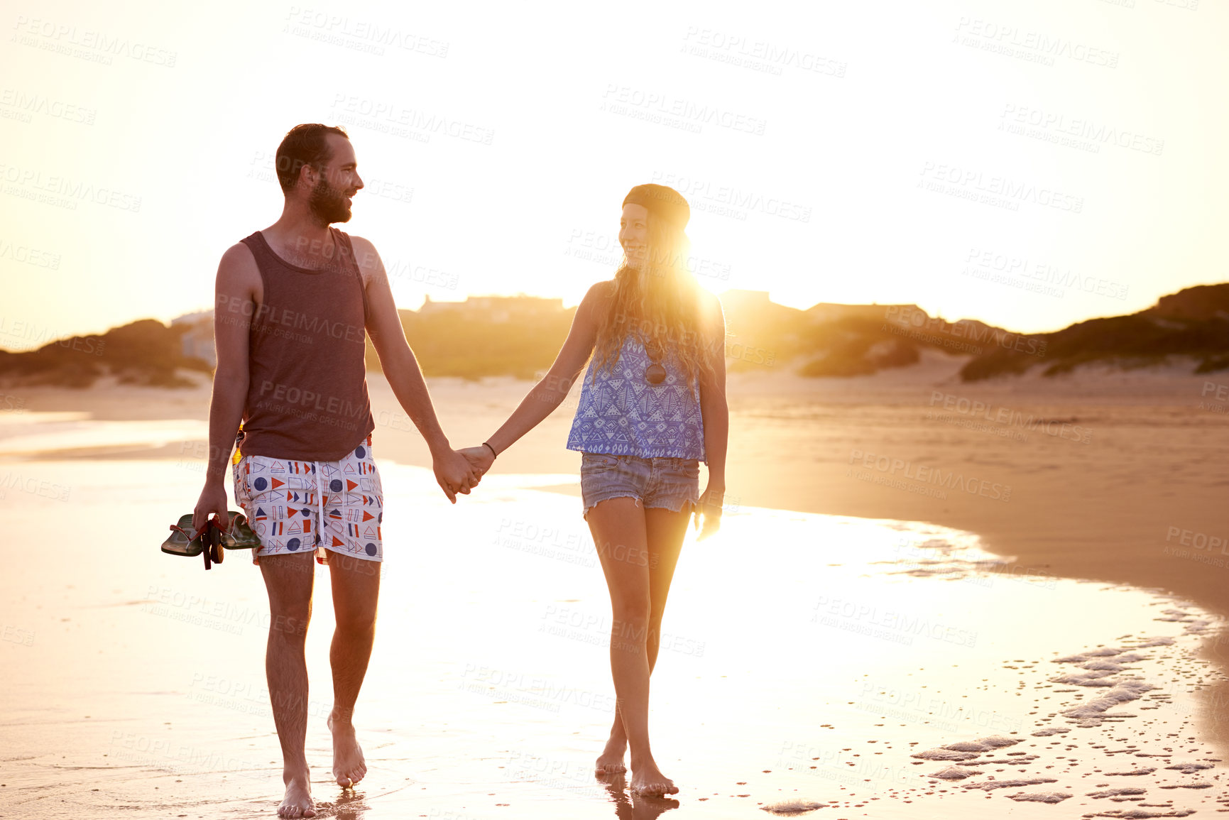 Buy stock photo Couple, sunset and holding hands at beach together for travel adventure, vacation and bonding. Flare, people and walking by seaside for sightseeing, exploring nature and relationship fun with romance