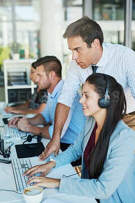 Buy stock photo Shot of a young man assisting his colleague in a call center