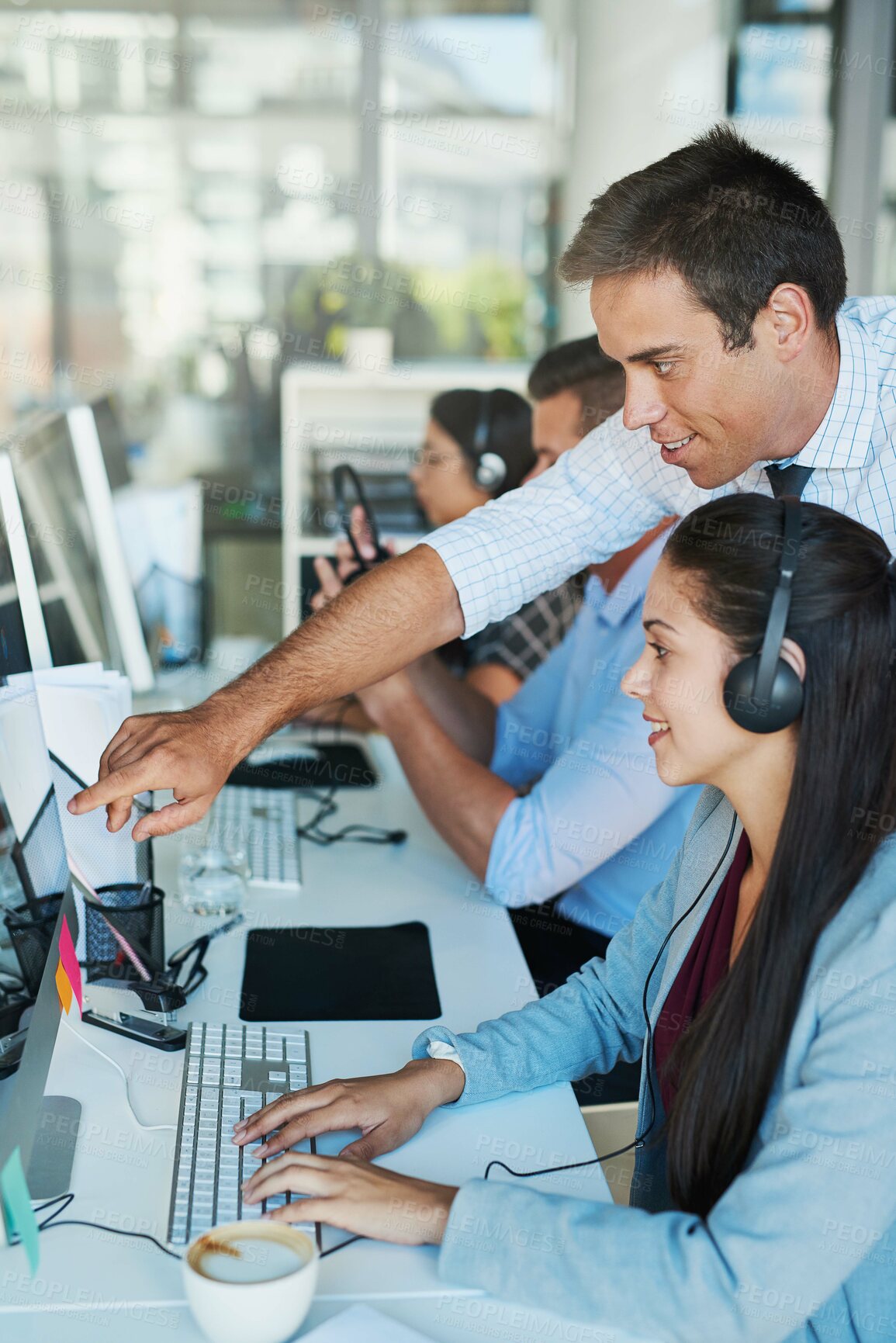 Buy stock photo Shot of a young man assisting his colleague in a call center