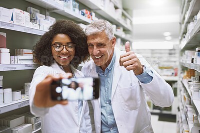 Buy stock photo Selfie, people and healthcare in pharmacy, smile and wellness of medicine, store and photography. Thumbs up, lab coat and pharmacist with mature man, shelf and confident with picture and memory