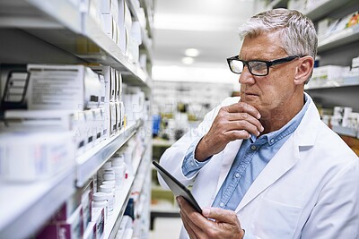 Buy stock photo Pharmacy, tablet and man or doctor by shelf with stock inventory, choice or decision for healthcare or medicine. Mature pharmacist thinking on digital tech for medical management and online solution