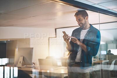 Buy stock photo Man, phone and texting in office, happy and overtime with update, reading and contact with app at night. Person, smartphone and check notification at startup, smile or web chat at creative agency