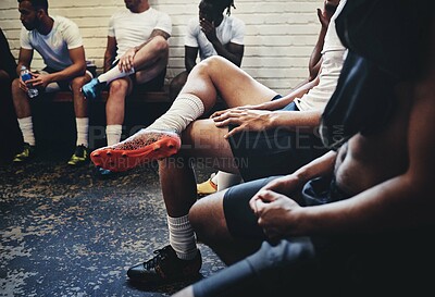 Buy stock photo Cropped shot of a group of unrecognizable rugby players sitting in a locker room during the day