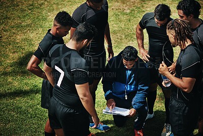 Buy stock photo High angle shot of a handsome young rugby coach addressing his team on the field during the day