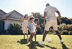 Happy mixed race family playing soccer outside in garden. Parents enjoying kicking a ball with their sons outside in the yard. Family bonding while playing together. Black family of four having fun