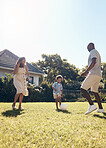 Happy mixed race family playing soccer outside in the garden at home. Parents enjoying kicking a ball with their son outside in the yard. Family bonding, having fun, playing together.