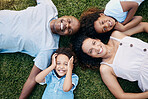 Above view of cheerful african american family lying in a circle. Dad, mom and their two lovely children lying on the grass looking at camera. Little boy and girl having fun with parents at park 