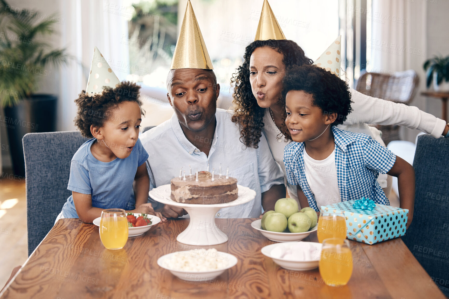 Buy stock photo Cake, candles and family at birthday in home for party, event or gathering together for bonding. Love, connection and children with parents for celebration with hats, gifts and dessert for tradition.