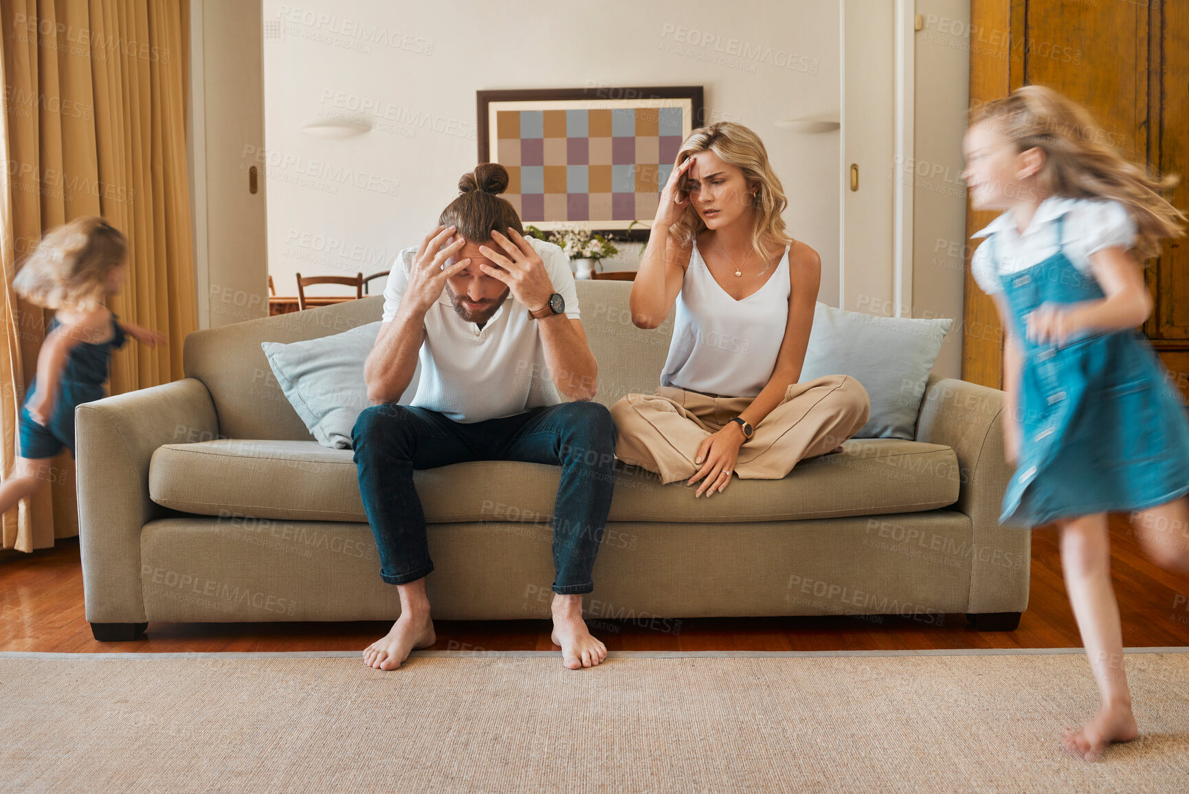 Buy stock photo Headache, motion blur and stress of parents with children running in living room of home for hyperactivity. ADHD, anxiety or energy with unhappy mom and dad on sofa in apartment for break or rest