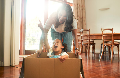 Buy stock photo Box, moving house and mother pushing daughter for having fun or playing game in new home together. Cardboard, pointing and smile of excited woman parent with girl in apartment for property investment