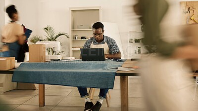 Buy stock photo Sustainable fashion designer, young man and creative working on a laptop in a busy ethical startup, textile workshop and manufacturing studio. Factory worker planning online orders for trendy clothes