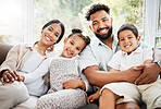 Portrait of a young hispanic family happily bonding together on the sofa at home. Mixed race mother and father sitting of the couch in the loung and looking happy while bonding with their cute little son and daughter