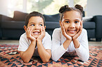 Portrait of two mixed race young siblings lying on the floor together at home and smiling. Little hispanic boy and girl having fun in the lounge at home