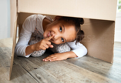 Buy stock photo Portrait, hiding and child playing in box in house for fun, fantasy and hide and seek games. Cardboard, happy girl and quiet kid in living room with smile, imagine and hush gesture in family home